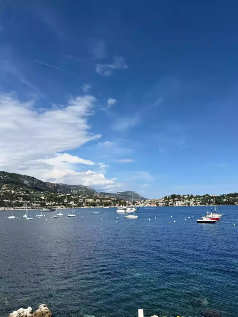 Vue de la baie de Villefranche-sur-Mer avec voiliers, mer bleue et reliefs de la Côte d’Azur.