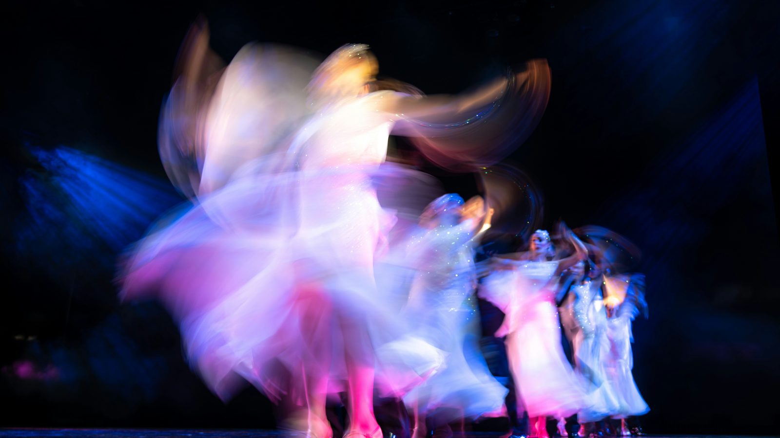 Danseuses en mouvement sous des lumières bleues et roses