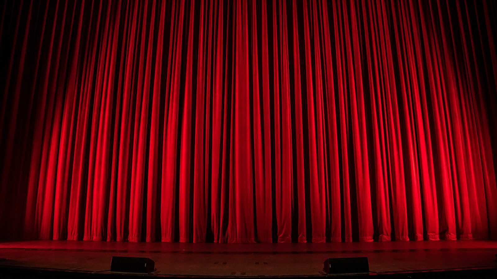 Grand rideau rouge fermé sur une scène de théâtre